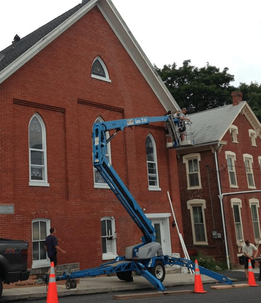 Roof repairs being performed on a church in Mechanicsburg, PA. The technician is using a lift to access the affect area of the roof.
