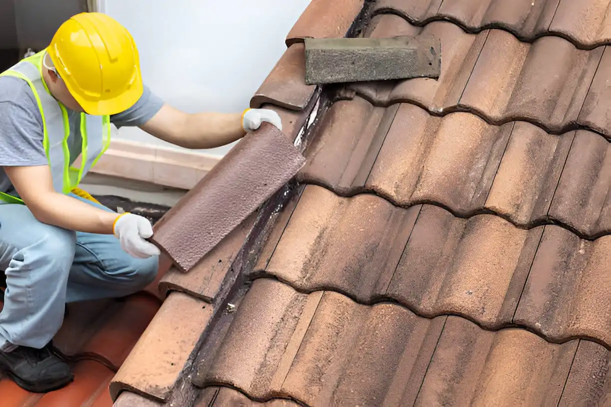 Worker fixing eaves and tiles of the old roof.