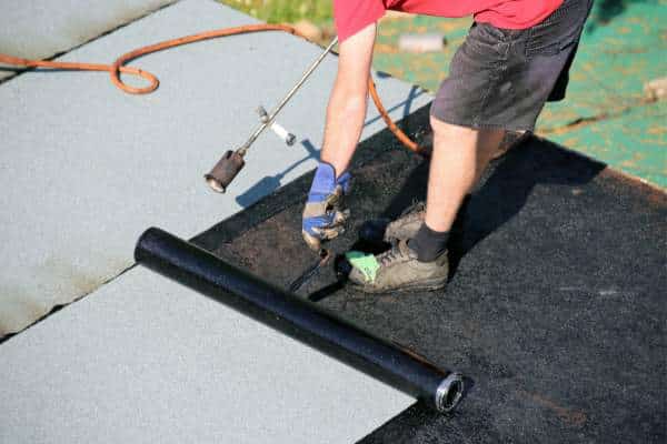 flat roof repair Flat roof repairs. A worker uses a torch to apply a modified bitumen flat roof covering