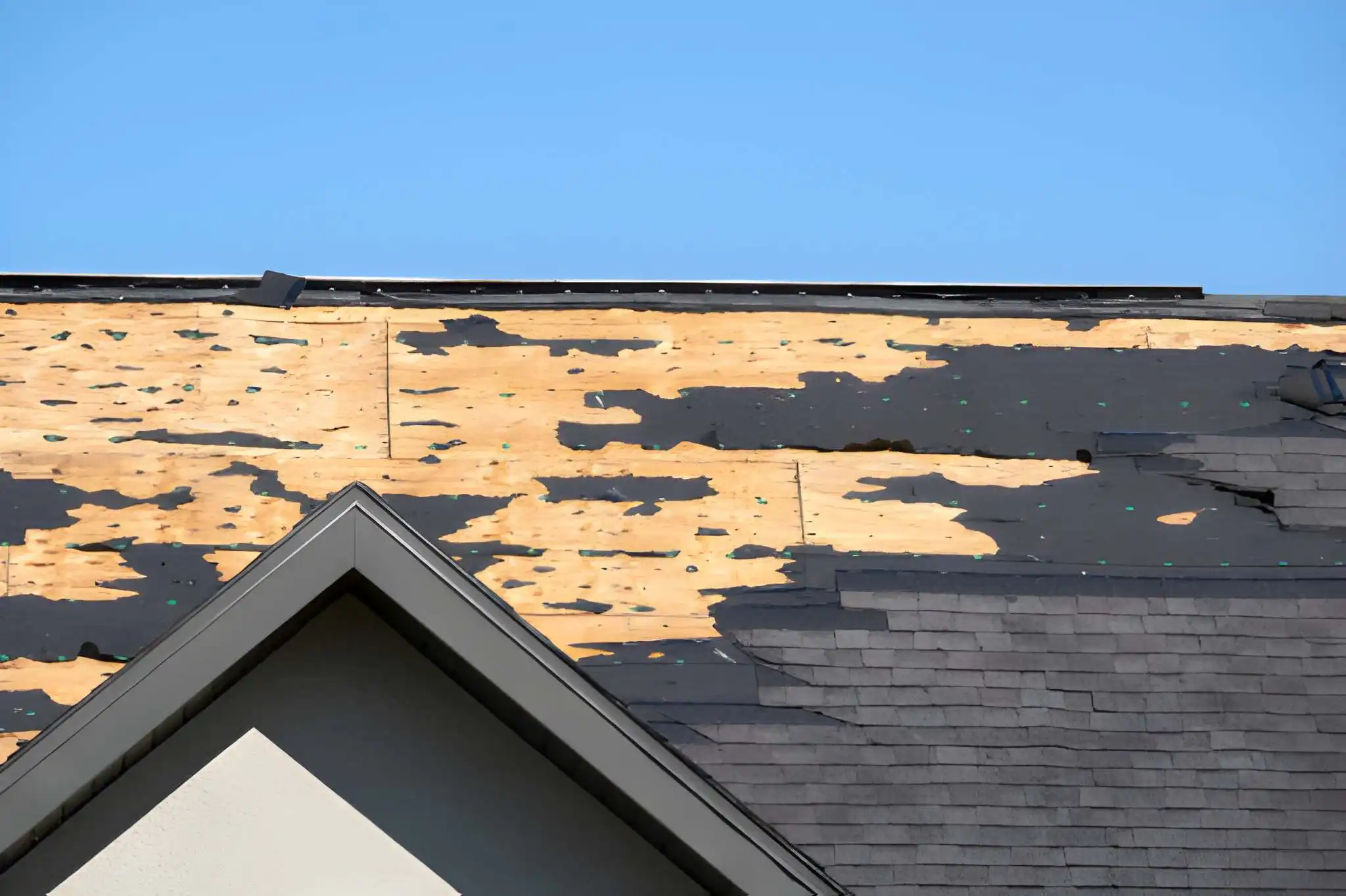 Damaged house roof with missing shingles after hurricane